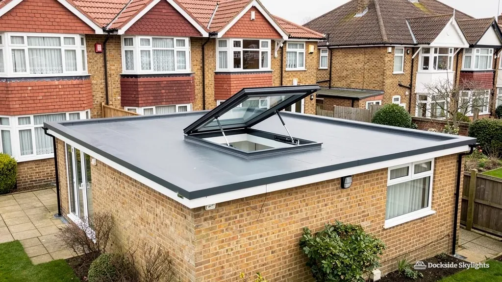 Electric rooflight standing open on a flat-roofed extension behind 1930s semis